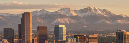 Snow-capped mountains rise behind the Denver city skyline