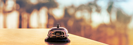 A silver service bell on a counter, with a beach scene in the background