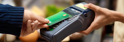 A customer taps a green credit card on a payment terminal for a contactless payment